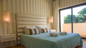 A hotel room with a large bed, striped walls, and a view through a window. - Apart Vilamoura Pine D'alma Portuguesa (Loulé)