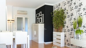 A modern living room with a dining area, a black accent wall, and a decorative plant arrangement. - Apart Vilamoura Pine D'alma Portuguesa (Loulé)