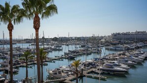 A marina with numerous boats docked, surrounded by palm trees and buildings in the background. - Apart Marina Boat View D`alma Portuguesa (Loulé)