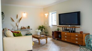 Een woonkamer met een bank, salontafel, televisie en een houten kast.