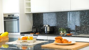 Een moderne keuken met een zwart granieten aanrecht, roestvrijstalen apparatuur en een koffiezetapparaat.