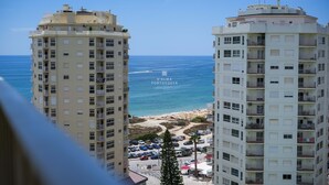 Dos edificios altos con balcones que dan a una playa y al mar.