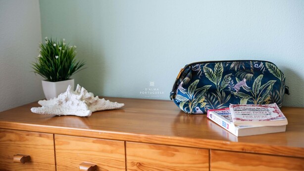 A wooden dresser with a potted plant, a decorative shell, and a bag with a tropical print. - Apart Lavanda Torre Castelo D´alma Port (Silves)