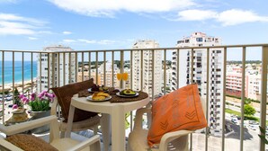 A balcony with a table set for breakfast, overlooking a beach and high-rise buildings. - Apart Lavanda Torre Castelo D´alma Port (Silves)