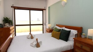 A hotel room with a large bed, wooden headboard, and a view of the beach through a large window. - Apart Anis Estrelado D´alma Portuguesa (Silves)