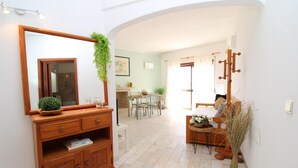 A well-lit hallway with a wooden console table, a mirror, and a potted plant. A dining area with a table and chairs is visible in the background. - Apart Anis Estrelado D´alma Portuguesa (Silves)