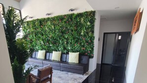A modern lobby with a black marble floor, a grey sofa with patterned cushions, and a green vertical garden wall. - U-SABAI VILLA  (Yasothon)