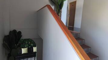 A staircase with wooden steps and a white handrail, leading to a landing with a potted plant and a small table with a plant on it.