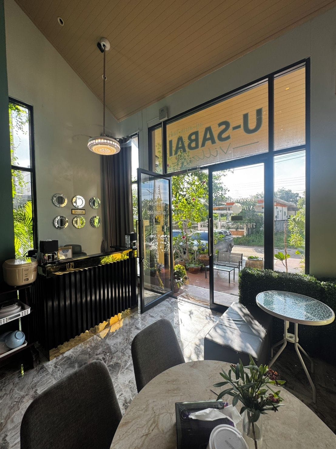 A modern interior with a reception desk, seating area, and large windows offering a view of the street.