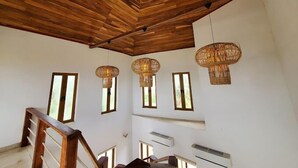 Un interior espacioso con un alto techo de madera, ventanas amplias y una escalera con barandilla de madera.