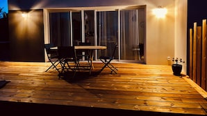 A modern patio with a wooden deck, a round table, and black chairs. - Seaside house Loctudy (Loctudy)