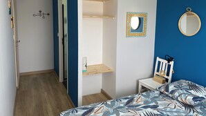 A bedroom with a bed, a bedside table, a mirror, and a hanging light fixture. - Seaside house Loctudy (Loctudy)