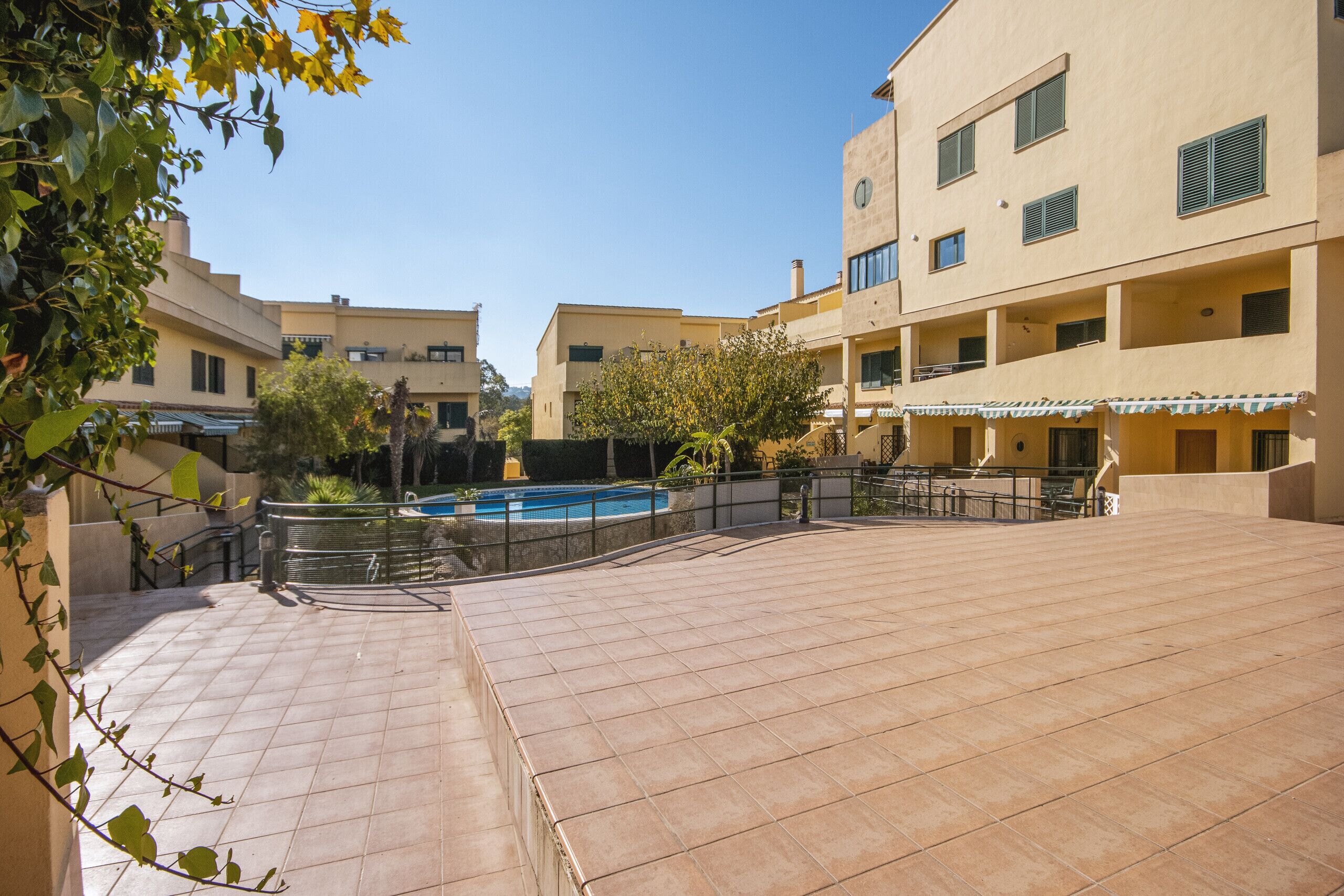 Une cour avec une piscine, entourée de bâtiments dotés de balcons et d’un espace salon couvert.