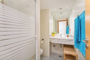 Une salle de bain équipée d’une douche, de toilettes, d’un lavabo et d’un miroir.