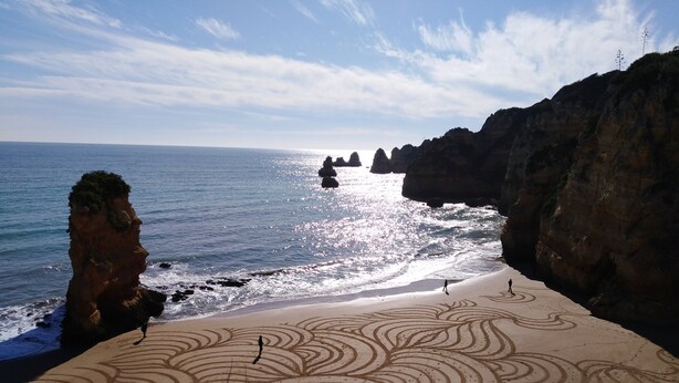 A beach with a large rock formation on the left and a patterned sand design in the foreground. - Fantastic Tranquil Apartment by the Pool (Lagos)