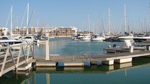 A marina with multiple boats docked, a wooden pier, and a building in the background. - Fantastic Tranquil Apartment by the Pool (Lagos)