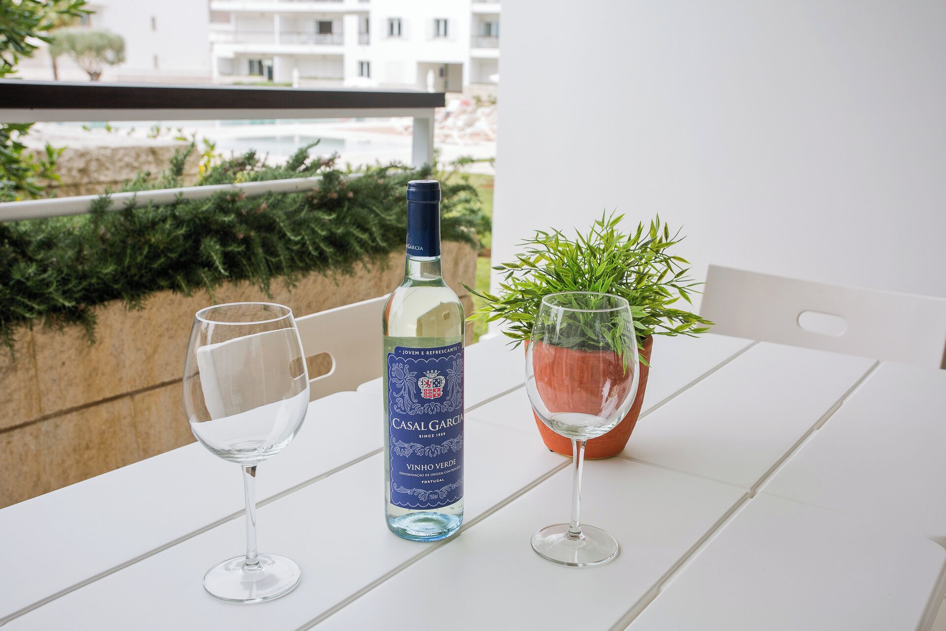 Et bord med to vinglas og en vinflaske på en balkon.