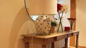 A wooden console table with a lamp, a mirror, and decorative items including flowers and a bowl. - Fantastic Tranquil Apartment by the Pool (Lagos)