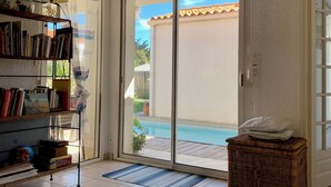 Quarto com estante, cesta de vime e porta de vidro corrediça para área da piscina.