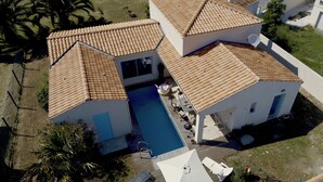 Uma casa de dois andares com piscina, varanda coberta e quintal cercado.