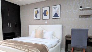 A bedroom with a bed, a desk, and a chair. There are three framed artworks on the wall. - Bamgbose Apartment  (Lagos)