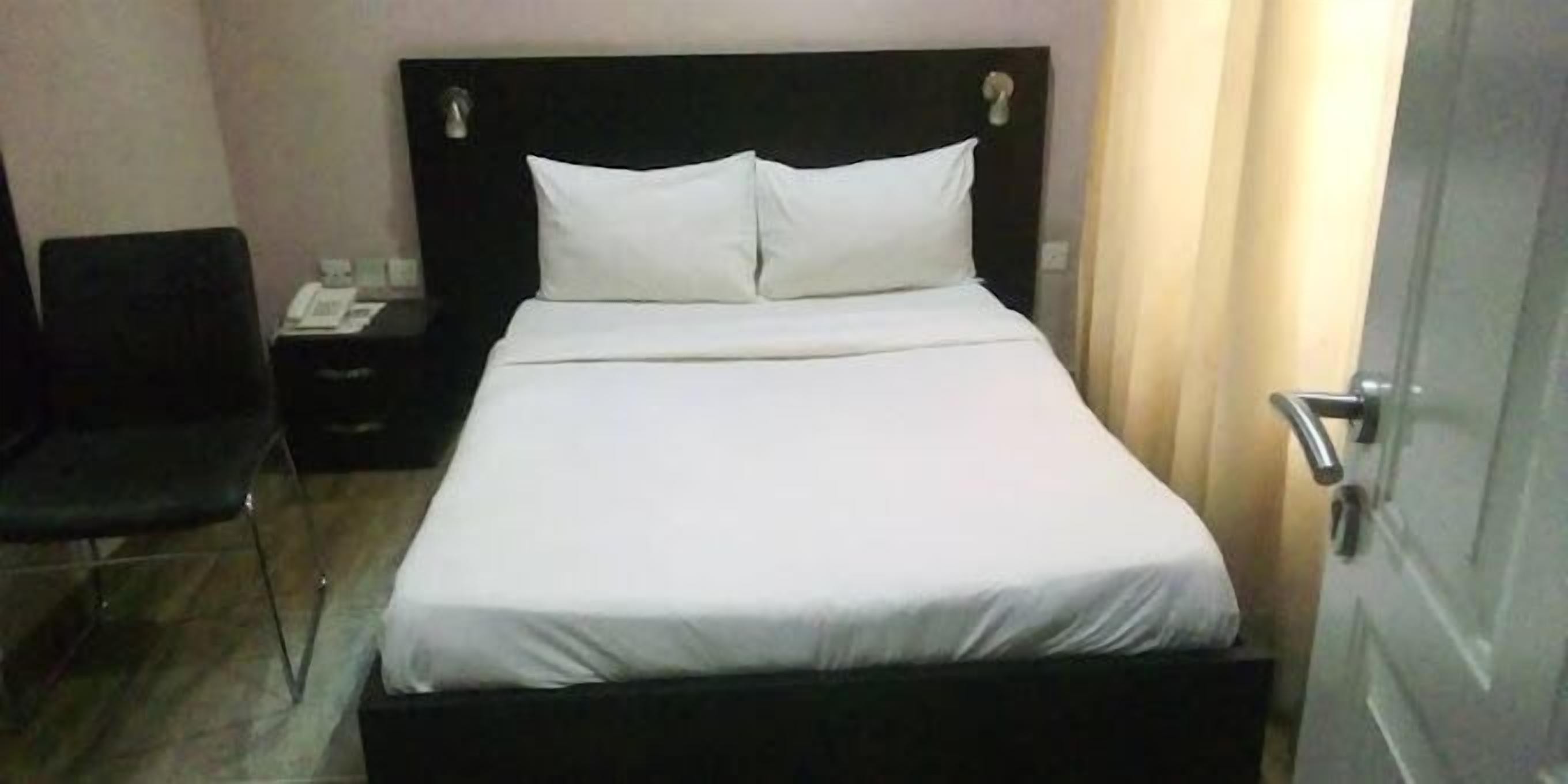 Un letto rifatto con lenzuola bianche in una camera d'albergo.