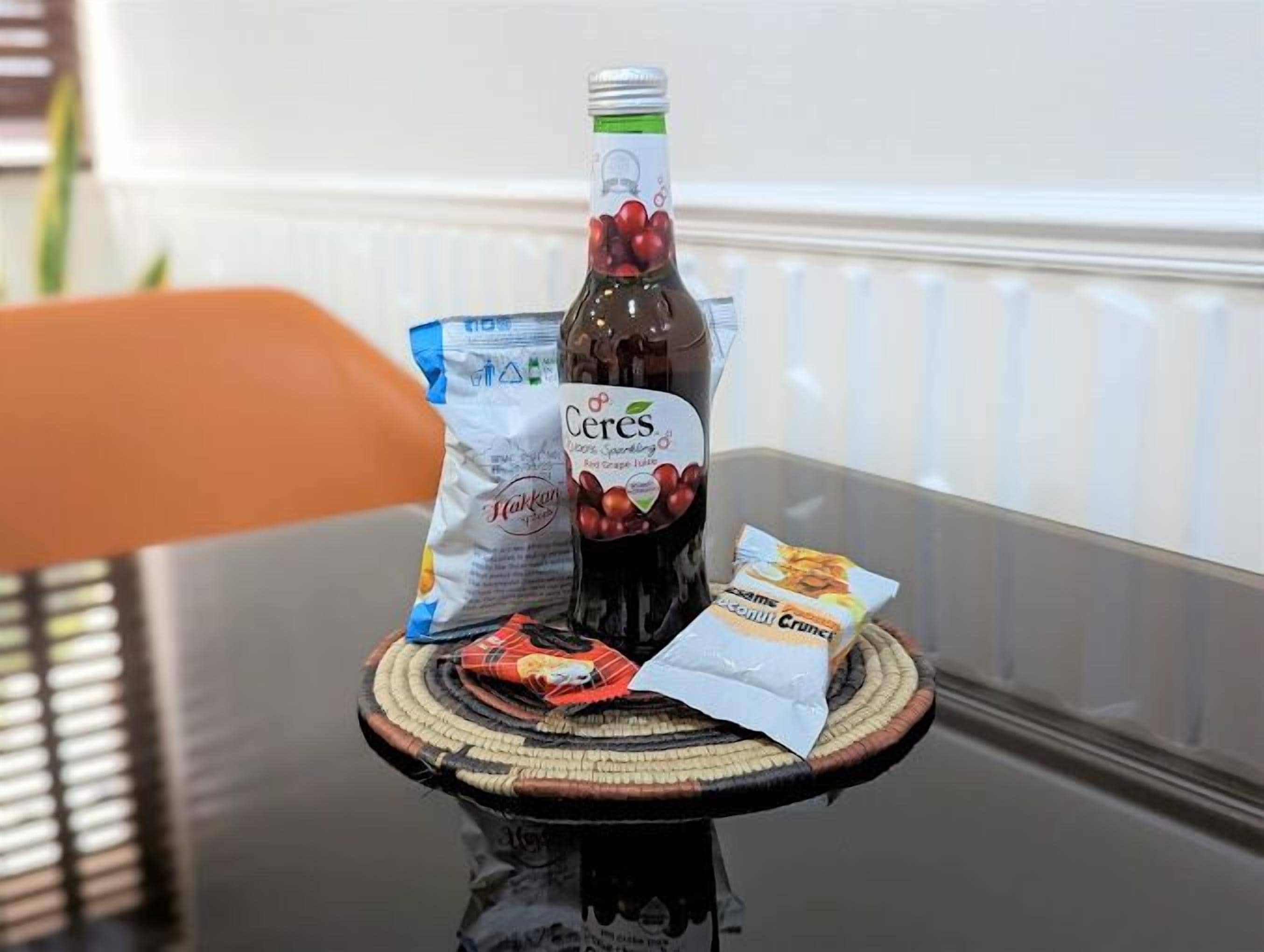A bottle of Cereals Red Grape Juice, a bag of Hakkala, and a packet of coconut flakes on a table.