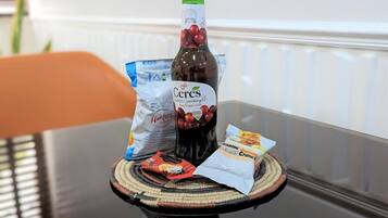 A bottle of Cereals Red Grape Juice, a bag of Hakkala, and a packet of coconut flakes on a table.