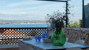 Eine Terrasse mit Tisch für zwei Personen, mit Blick auf die Küste.