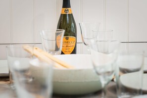 A bottle of rosé wine, a wooden spoon, and several glasses on a table. - Host Stay Coombe Cottage (Lyme Regis)