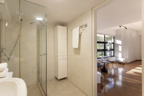 A modern bathroom with a glass shower enclosure, a white cabinet, and a glass door. - Spacious Apartment With Monumental View (Athens)
