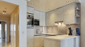 A modern kitchen with a central island, built-in appliances, and a minimalist design. - Flat in Blankenberge With Ocean Views (Blankenberge)
