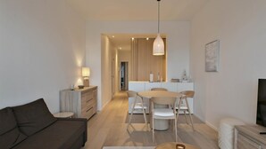 A modern living room with a sofa, a coffee table, and a dining area with a table and chairs. - Flat in Blankenberge Near Belgium Pier (Blankenberge)