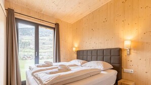 A bedroom with a large bed, wooden walls, a window with curtains, and a nightstand. - Attractive Apartment With Sauna (Sankt Georgen am Kreischberg)