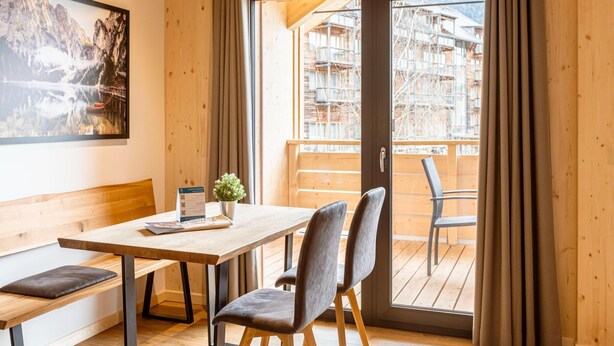 A wooden interior with a table and chairs, a bench, a door with curtains, and a framed picture on the wall. - Attractive Apartment With Sauna (Sankt Georgen am Kreischberg)