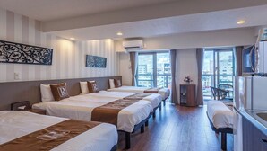 A hotel room with three beds, a TV, a minibar, and a city view.
