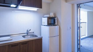 A compact kitchen with a microwave, refrigerator, and sink.