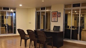 Una sala de conferencias con piso de madera, un mostrador de recepción y sillas de plástico.