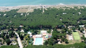 An aerial view of a residential area with a large swimming pool, tennis courts, and a beach in the background. - ITALY VILLAGE (Sessa Aurunca)