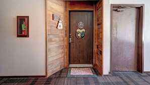 Una porta di legno con un tappetino d'ingresso, una decorazione a forma di pupazzo di neve e un quadro appeso al muro.
