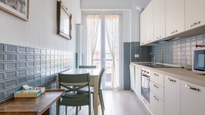 A modern kitchen with a dining area, featuring a tiled backsplash, a wooden table, and a green chair.