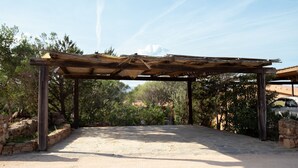 A covered outdoor area with stone walls and a wooden pergola.