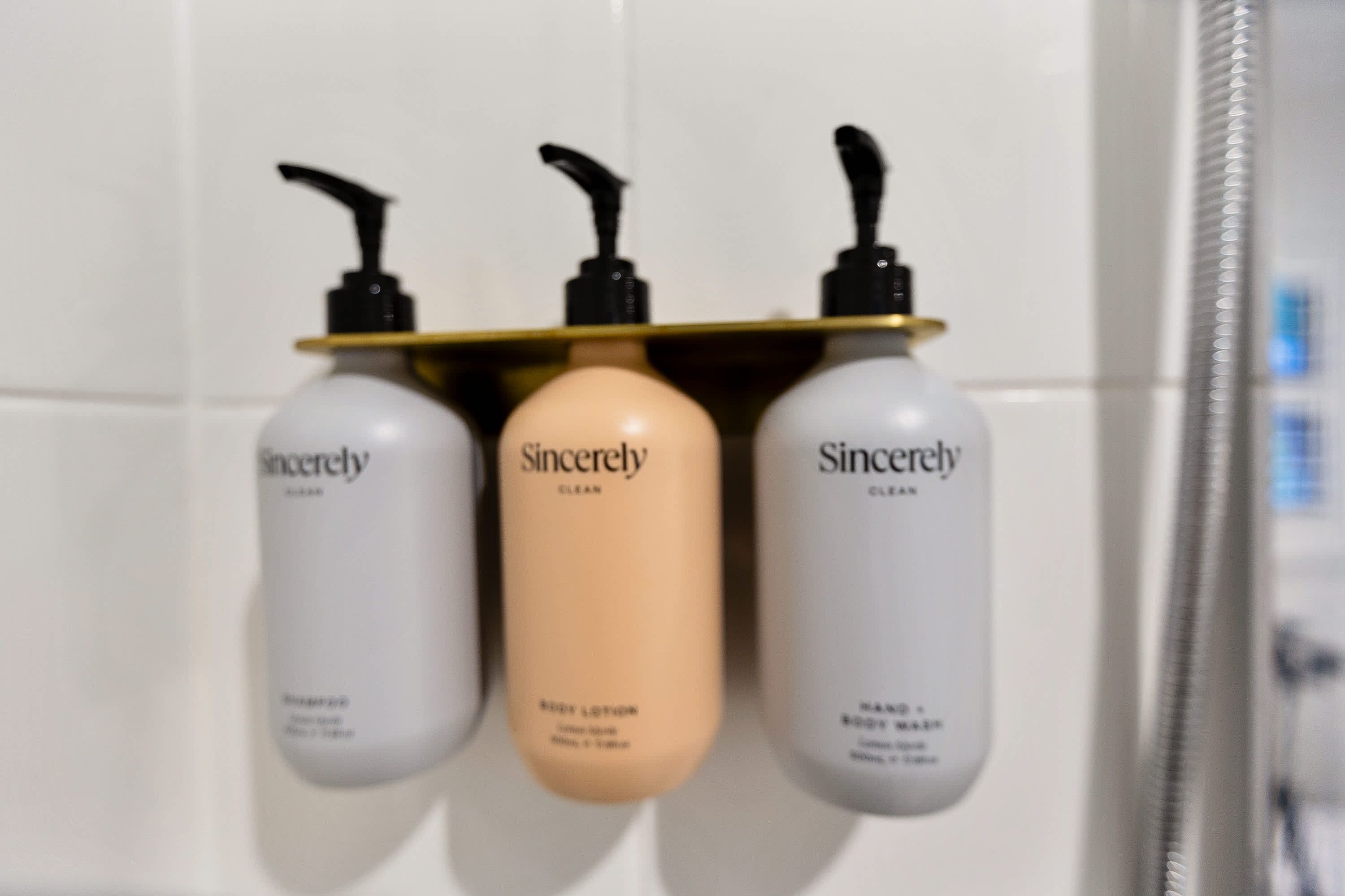 Three Sincerely Clean bottles on a white tiled wall.
