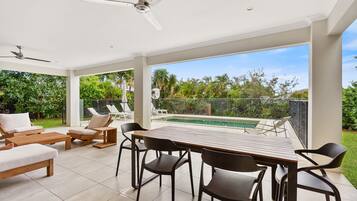 Un patio amplio con piscina, mobiliario exterior y vistas a la vegetación.
