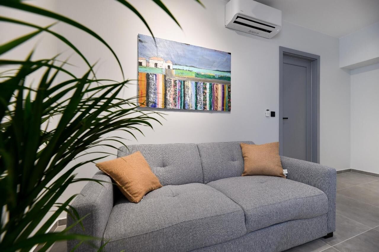 A grey sofa with two brown cushions in a room with a white wall and a door.