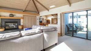 A living room with a fireplace, a sofa, and a glass door leading to an outdoor area. - Amazing Oceanview's - Dog-Friendly 4BR with Sauna (Bodega Bay)