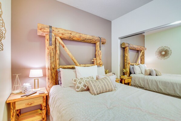 A bedroom with a wooden headboard, a bedside table with a lamp, and a mirror.