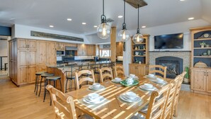 A spacious kitchen with wooden cabinets, a dining table set for six, and a fireplace. - Game Room, Media Room & Pool: Luxe Villa in Craig! (Craig)