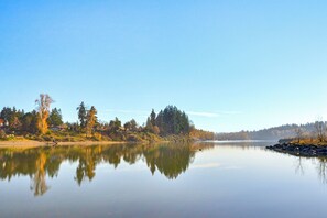 Ein ruhiger See mit Spiegelungen von Bäumen und einem klaren Himmel.