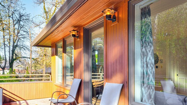 Une façade en bois, de grandes fenêtres et deux chaises sur un balcon.